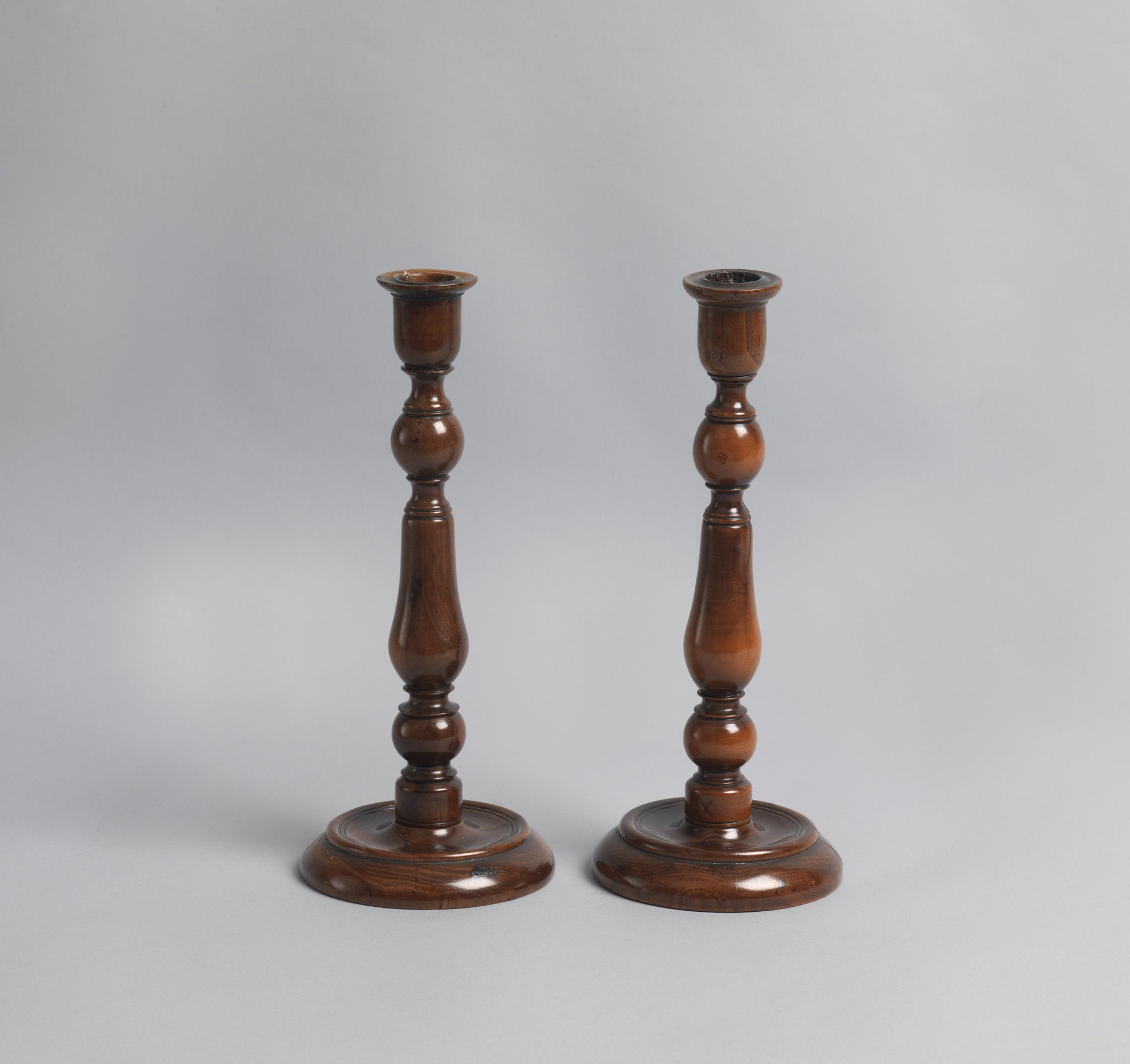 A Pair of Early Yew Wood Table Candlesticks